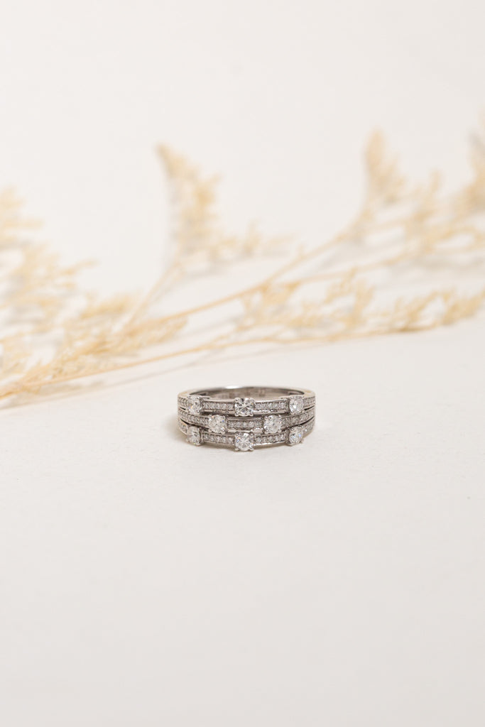 White gold wide diamond dress ring which is crafted to look like a stack of three different rings.