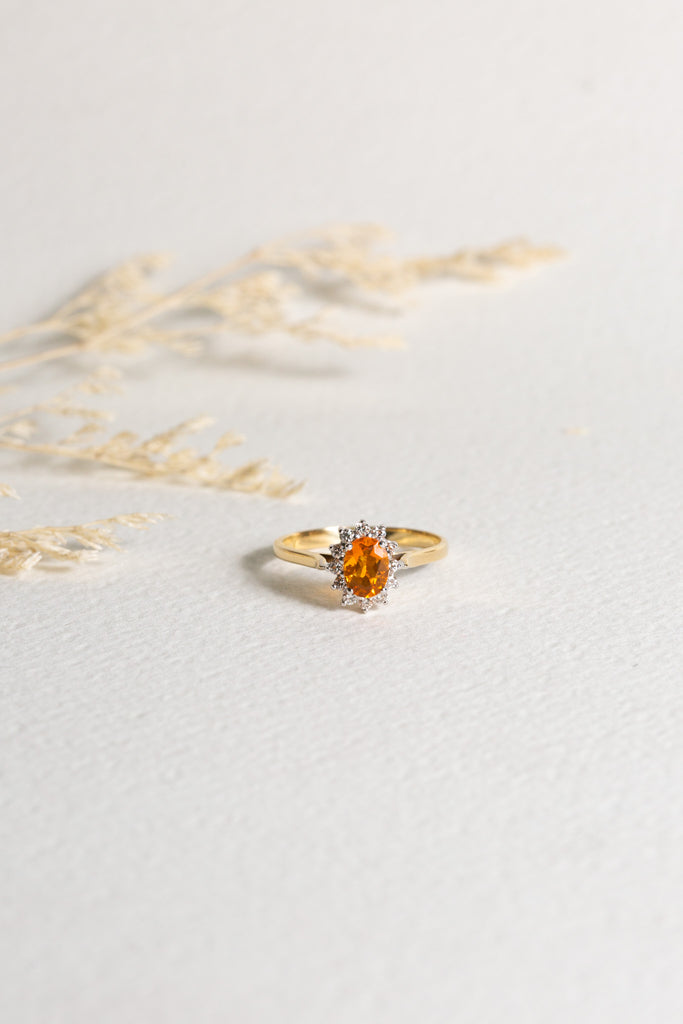 18ct gold ring set with a Fire Opal, which is surrounded by diamonds.