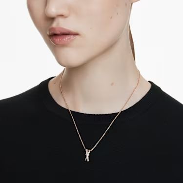 A model is wearing a rose gold Swarovski pendant