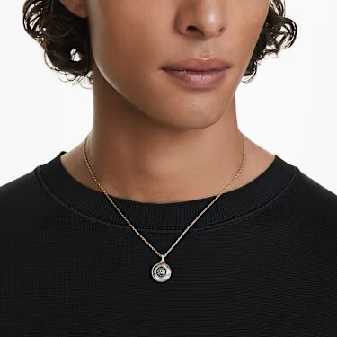 A model is wearing a gold evil eye pendant made from Swarovski crystal